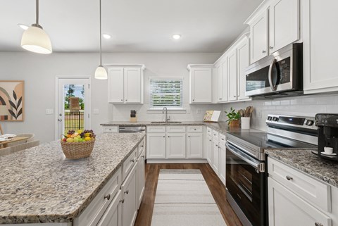 a large kitchen with granite counter tops and white cabinets