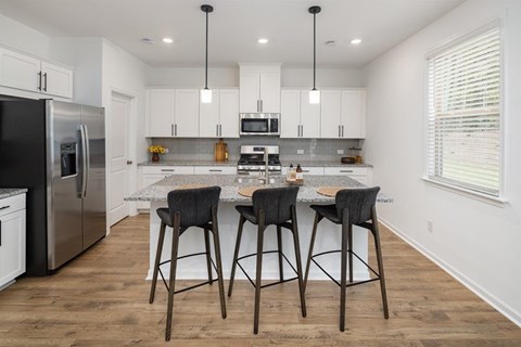 A kitchen with a bar stool in front of the island.