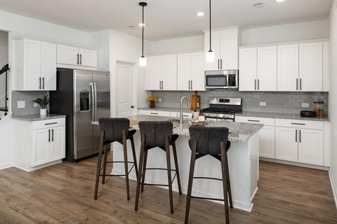 A kitchen with white cabinets and a black refrigerator.
