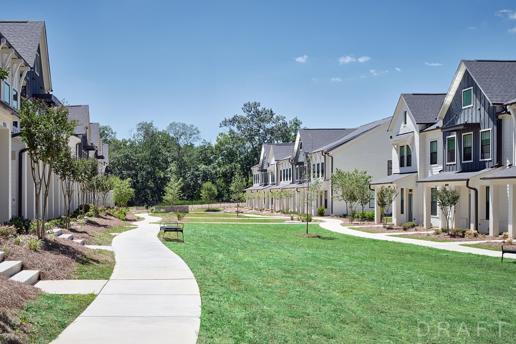 a row of houses with a green lawn and a sidewalk