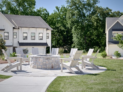 Outdoor gathering space with comfortable chairs and a warm fire pit centerpiece.