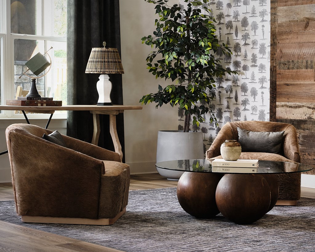 a living room with two brown chairs and a glass coffee table
