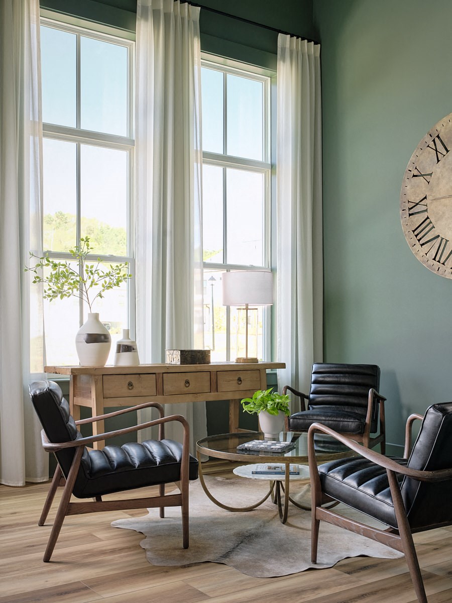 a living room with two chairs and a table and a clock on the wall