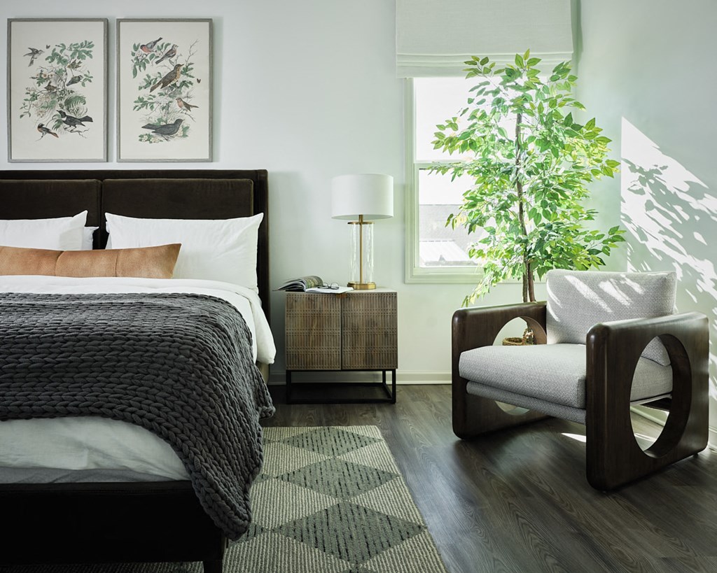 a bedroom with a bed and a chair and a plant