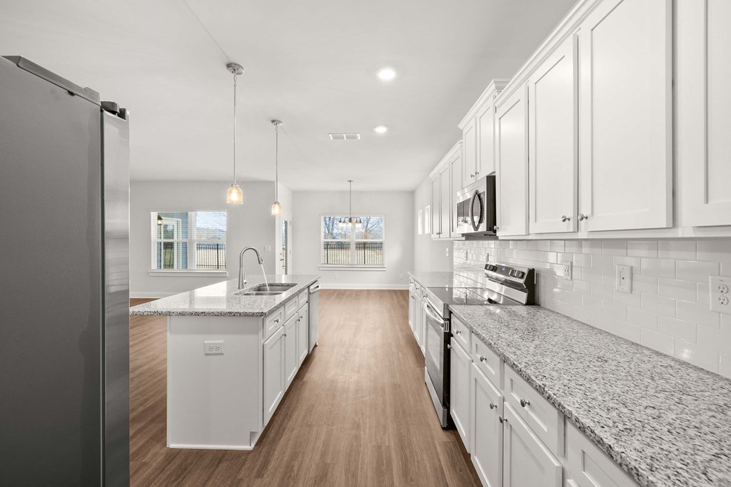 a large kitchen with marble counter tops and white cabinets