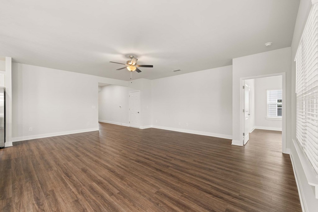 an empty living room with white walls and a ceiling fan