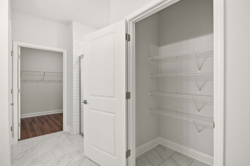 the closet in a bedroom with white closets and a door open
