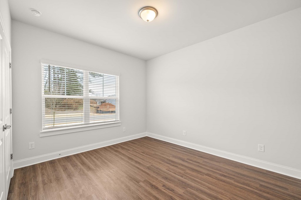 an empty living room with wood floors and a window