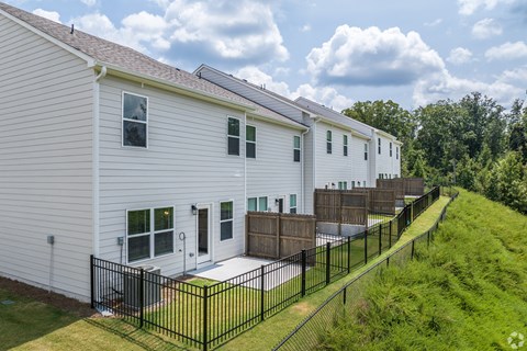 A white house with a black fence and a green lawn.