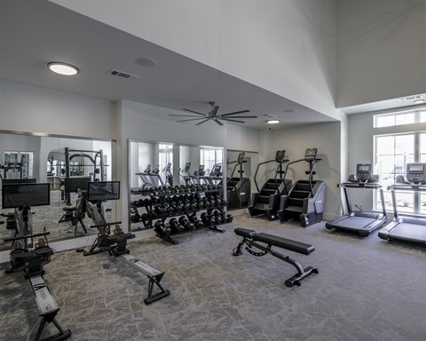 A spacious gym with a variety of equipment including treadmills, stationary bikes, and weight machines.