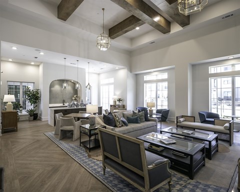 A large, well-lit living room with a variety of seating options and a central coffee table.