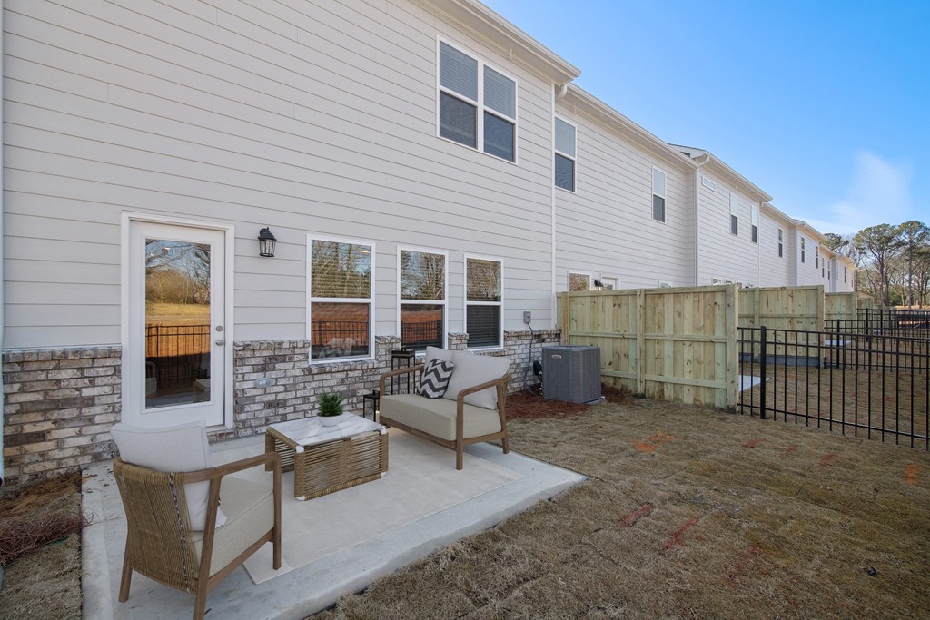 a patio with two chairs and a table in front of a house