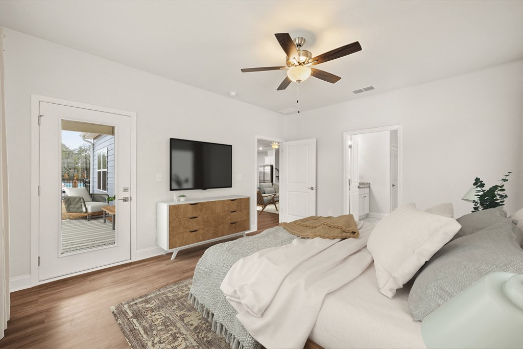 Primary suite featuring a contemporary ceiling fan, stylish entertainment area, and bright, sunlit windows.