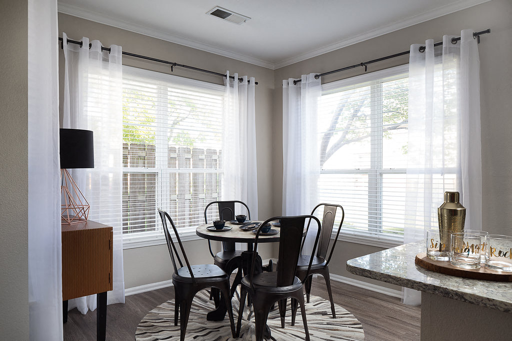 City Place at Westport - Furnished Dining Room With Circular Table, Chairs, and Windows With Blinds and Curtains