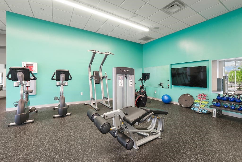 a gym with various exercise equipment and a television