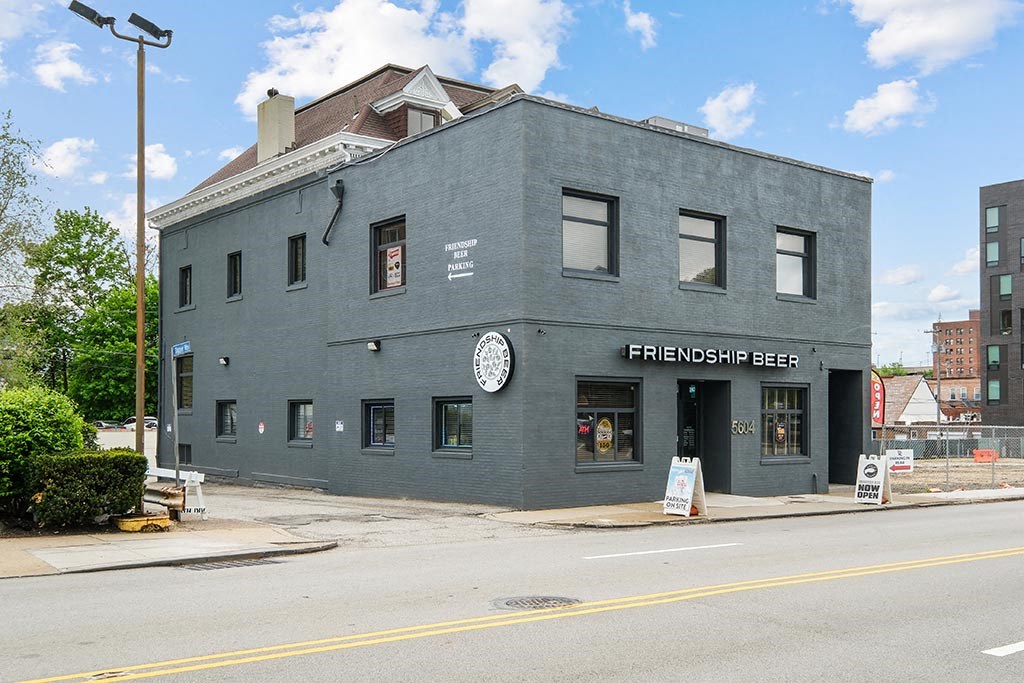 a gray building with a clock on the side of a street