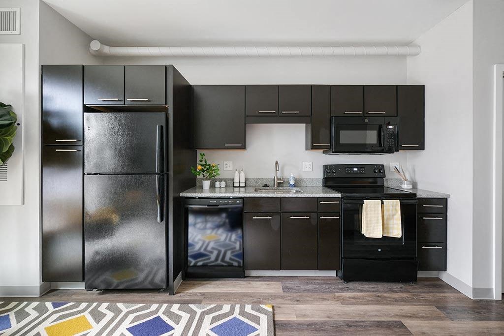 a kitchen with black cabinets and a stainless steel refrigerator
