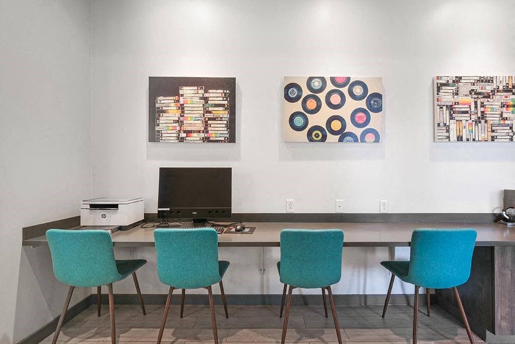 a desk with four blue chairs and a computer in a room