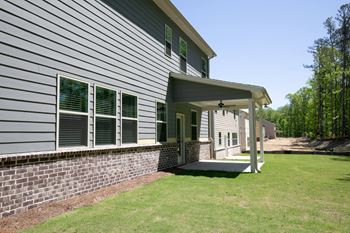 the front of the house has a porch and a brick retaining wall