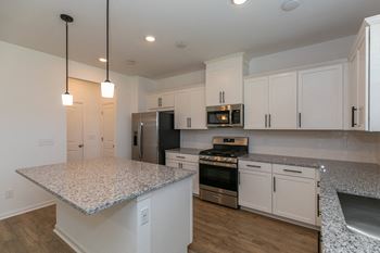 a kitchen with white cabinets and a marble counter top