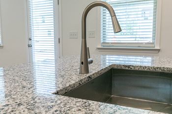a kitchen sink with a faucet on a granite counter top