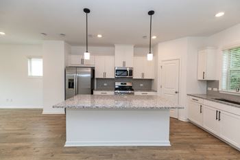 a kitchen with white cabinets and a marble counter top