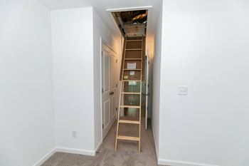 an empty room with a ladder and a hallway with a door