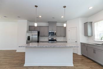a kitchen with an island with granite counter top and a stainless steel refrigerator