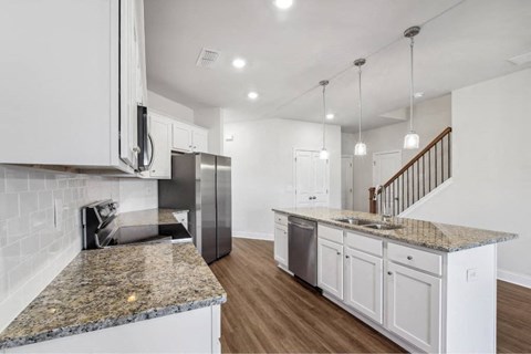 a kitchen with granite counter tops and white cabinets