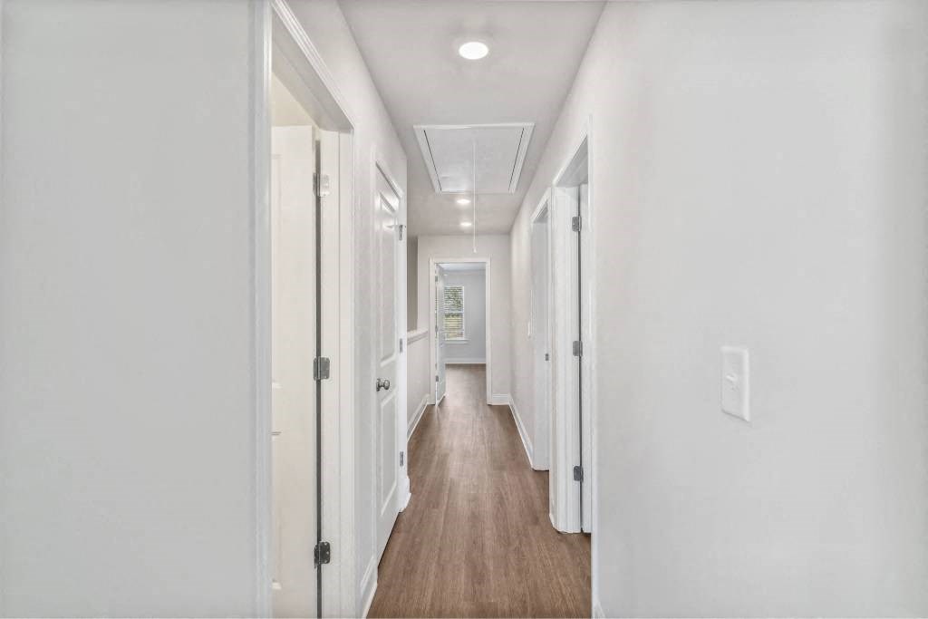 A bright hallway featuring warm wood flooring.