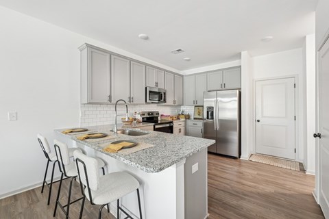 View of the kitchen and entry hallway. Offering bar seating, plenty of cabinet space and granite countertops.