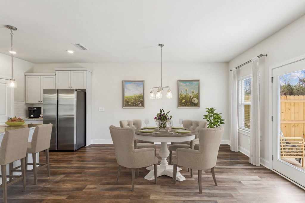 a dining room with a table and chairs and a kitchen with a refrigerator