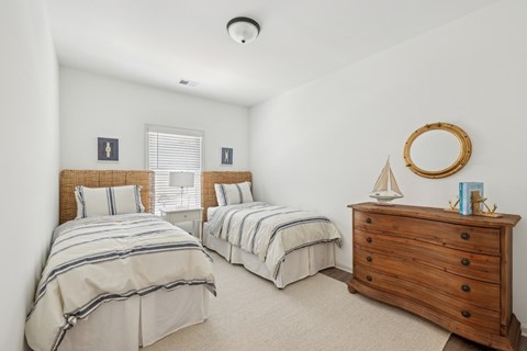 Charming third bedroom featuring two twin beds and a nightstand adorned with a sailboat accent.