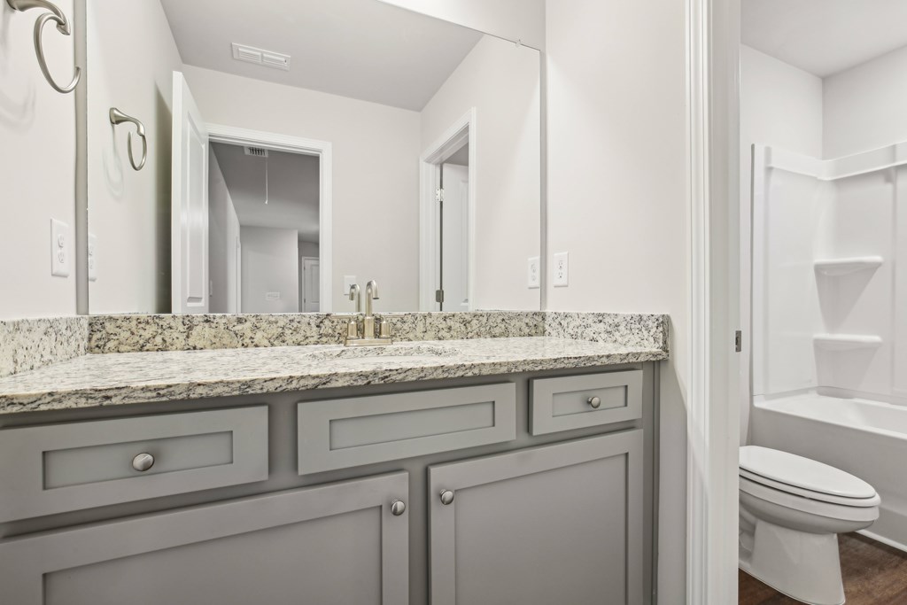 Elegant primary bath with granite countertops, and tub-shower combo.