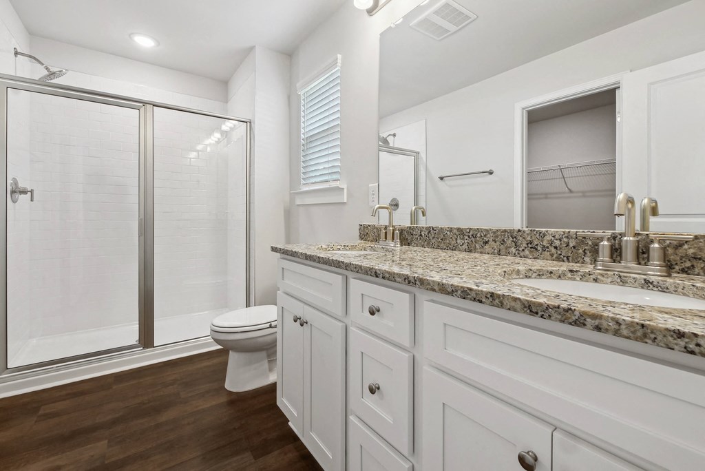 Primary bathroom featuring a double vanity and walk-in shower.