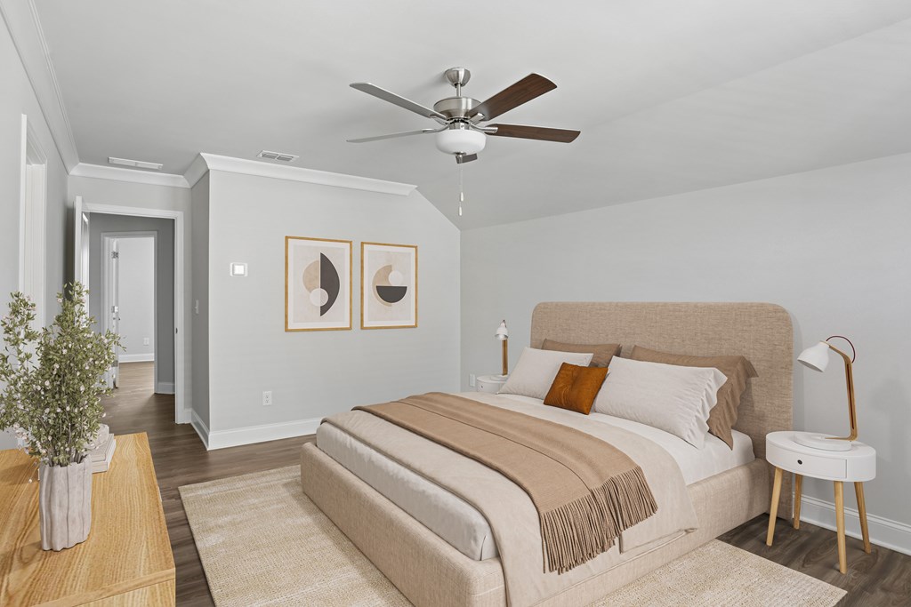 Primary bedroom with a plush bed, ceiling fan, and charming plant-accented table.