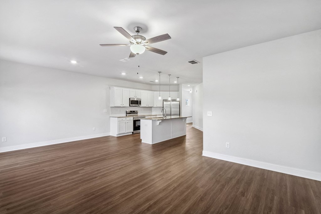a living room with white walls and a ceiling fan