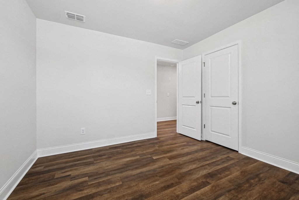 a bedroom with white walls and wood flooring and white doors