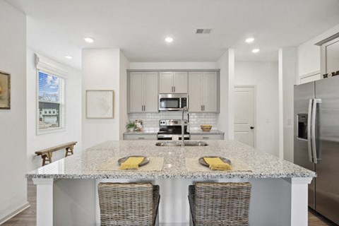 View of the kitchen and entry hallway. Offering bar seating, plenty of cabinet space and granite countertops.