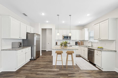 a large kitchen with white cabinets and stainless steel appliances