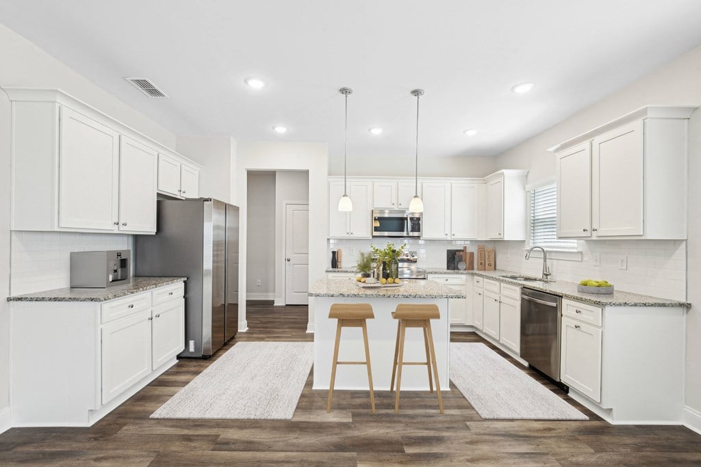 View of the kitchen and entry hallway. Offering bar seating, plenty of cabinet space and granite countertops.