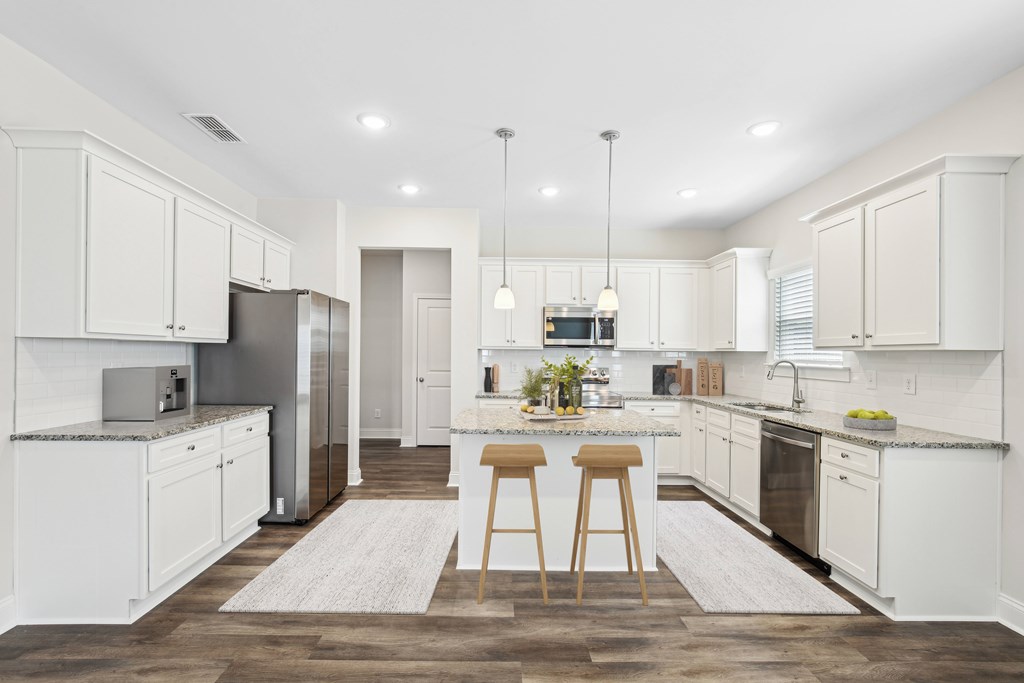 View of the kitchen and entry hallway. Offering bar seating, plenty of cabinet space and granite countertops.