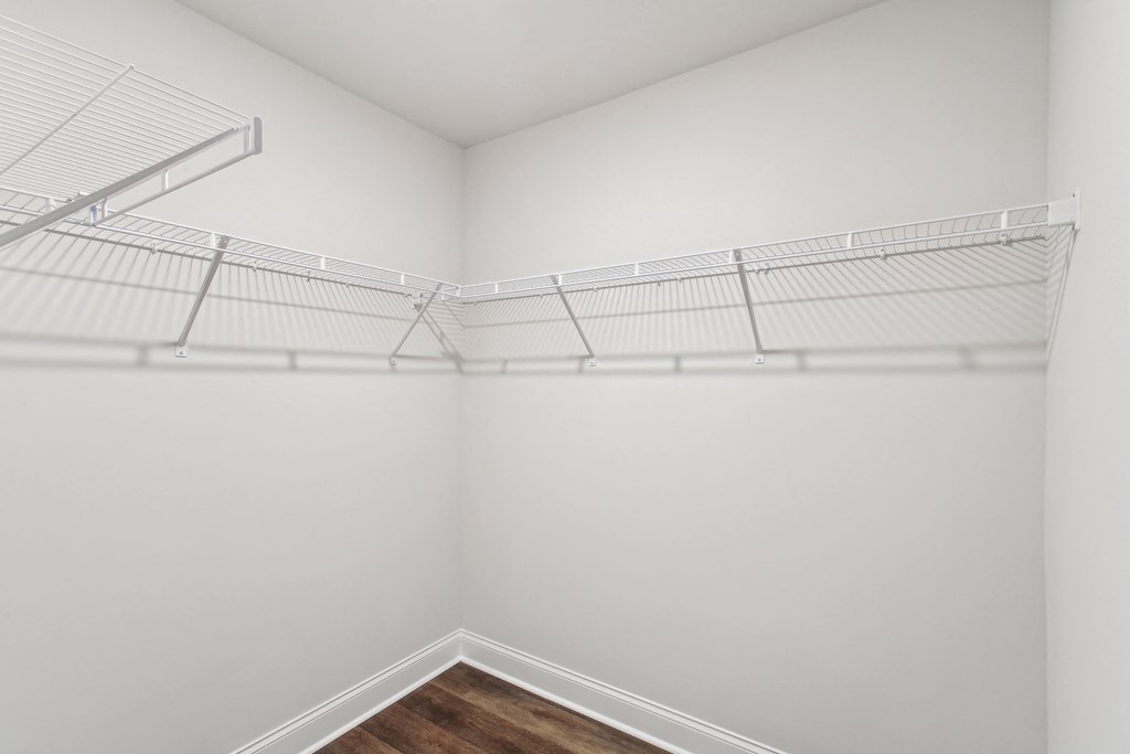 an empty closet with white walls and a wood floor