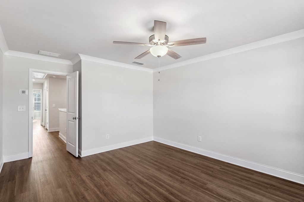 an empty living room with white walls and a ceiling fan