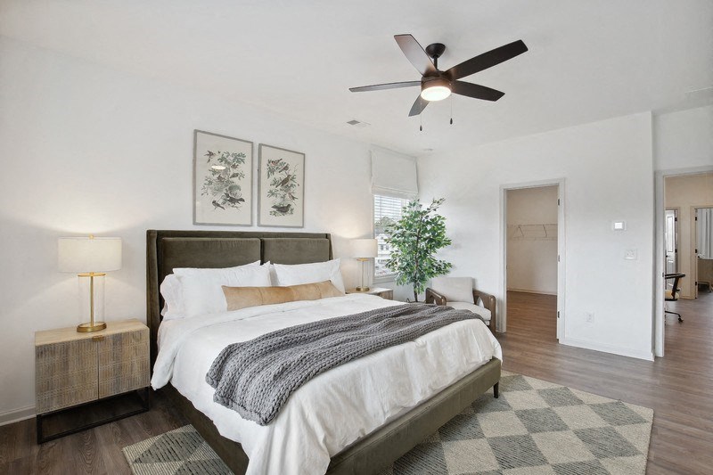 the master bedroom has a large bed and a ceiling fan