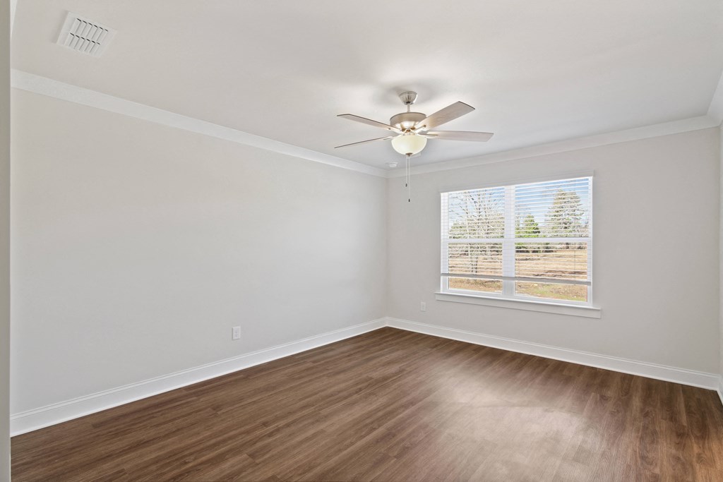 an empty living room with a ceiling fan and a window