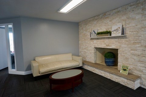A living room with a white couch and a stone fireplace.