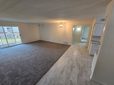 A spacious room with a carpeted floor and a window.