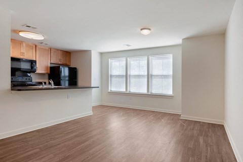an empty living room and kitchen with wood flooring and a window