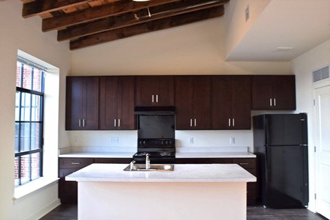 a kitchen with a white counter top and a black refrigerator
